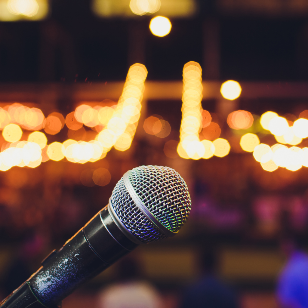 Microphone in the foreground of a nightclub featuring a stand-up comedian